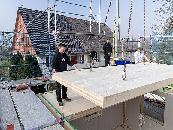 Zimmerer montieren auf der Baustelle ein Deckenelement.