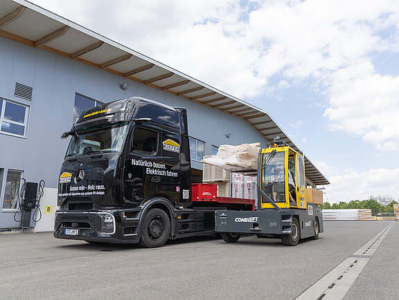 Ein Mercedes-Benz eActros wird von einem Combilift Mehrwege-Gabelstapler beim Beladen unterst&uuml;tzt.